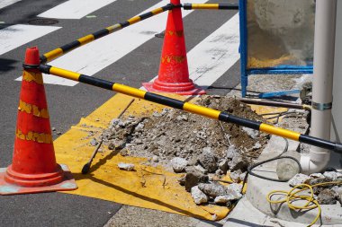 Yaya geçidinin yakınındaki kırık betonu çevreleyen turuncu trafik konileri