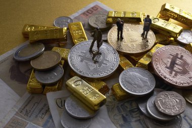 Bozuk para, bitcoin ve altın külçelerin üzerinde duran işadamlarının minyatür figürleri