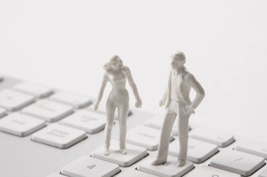 Beyaz arka planda bilgisayar klavyesinde duran iki minyatür insan. İnsan heykelcikleri maket yapar
