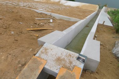 Kum ve inşaat malzemeleriyle çevrili beton kanal