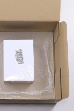 Üzerinde barkod olan beyaz kutu daha büyük bir karton kutunun içinde temiz bir filme sarılmış.