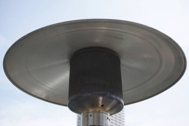 Parlak gökyüzü arka planında duran büyük metalik ısıtıcı