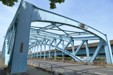 Mavi metal köprü, açık gökyüzünün altında yol boyunca yaylanıyor.