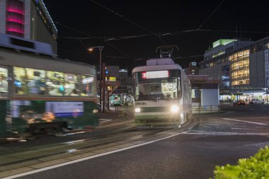 Alacakaranlık vakti kalabalık Japon şehrinden geçen tramvaylar. 