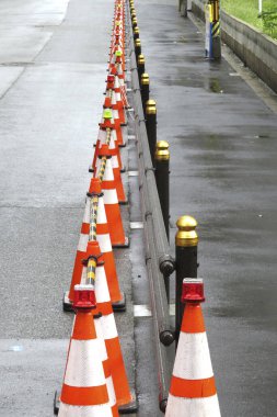 Turuncu trafik konileri ıslak yol yüzeyi boyunca dizildi