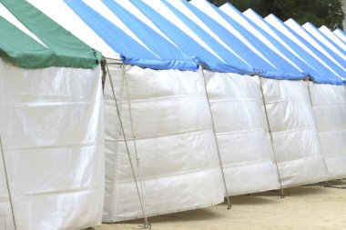 Mavi ve yeşil çizgili beyaz çadırlar.