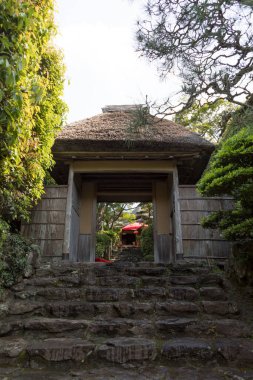 Çevresi yeşilliklerle çevrili geleneksel binaya giden taş basamaklar.
