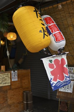 Geleneksel ahşap mağaza girişinin dışında asılı renkli Japon fenerleri.