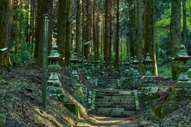 Merdivenleri, heykelleri ve yeşil ağaçları olan Japon bahçesi.