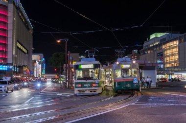Alacakaranlık vakti kalabalık Japon şehrinden geçen tramvaylar. 