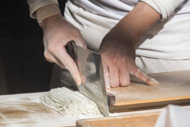 Geleneksel İtalyan makarnası yapma süreci. Usta masada hamuru kesiyor