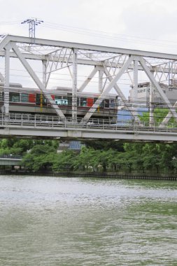 Metal köprüyü geçen tren sakin su gövdesinin üzerinde