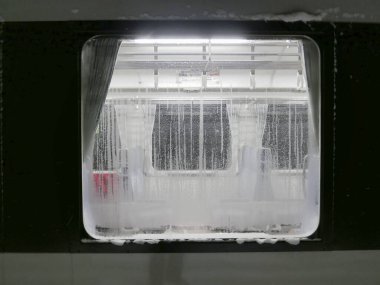 Boş trenin iç tarafındaki buzlu metro penceresinden bakıyorum.
