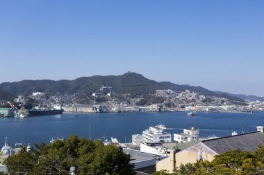 Mavi liman suyu açık gökyüzü altındaki şehir binalarını yansıtıyor.