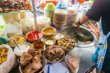 Sokak satıcısı çeşitli erişte yemekleri hazırlıyor.