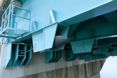 Yakın plan, beton destek kirişlerinin üzerindeki mavi çelik köprü yapısını gösteriyor