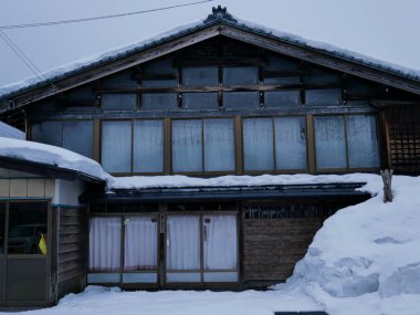 Geleneksel ahşap ev, derin kış akşamlarıyla kaplı.