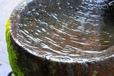 Su, dışarıdaki taş havuzda yavaşça akıyor.