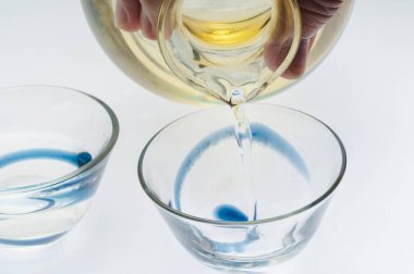 Mavi kıvrımlı cam kaseye temiz sıvı dökülüyor.