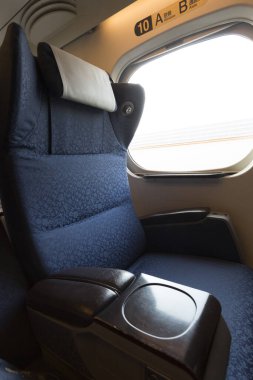 Pencerenin yanındaki yumuşak kumaşlı boş uçak koltuğu