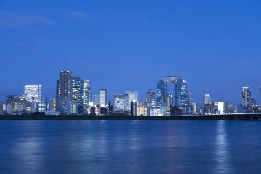 Aydınlatılmış binaların ve su kütlesinin gece manzarası          