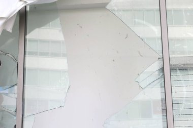 Yakınlardaki modern binayı yansıtan büyük kırık cam pencereler.