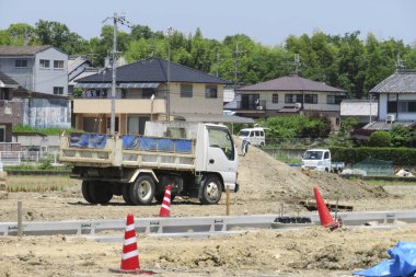İnşaat alanı kamyon, evler, yol ve trafik konilerini gösteriyor