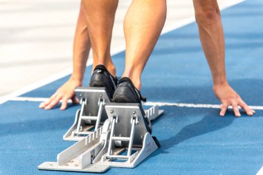 Stadyumda koşu bandında koşan bir adamın bacakları.