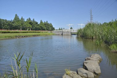 Sakin nehir berrak gökyüzünün altında beton baraja doğru akıyor.