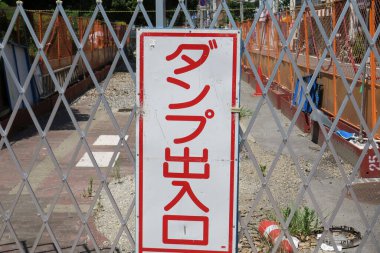 İnşaat alanını çevreleyen metal çitler Japon uyarı levhasıyla çevrili.