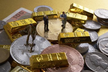 Bozuk para, bitcoin ve altın külçelerin üzerinde duran işadamlarının minyatür figürleri