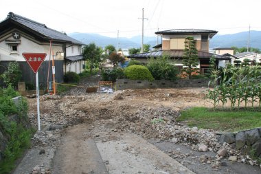 Enkaz ve inşaat gösteren evlerin yakınındaki kırsal yol hasar görmüş.