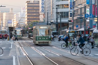 Alacakaranlık vakti kalabalık Japon şehrinden geçen tramvaylar. 