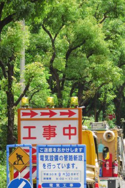 Yol boyunca ağaçlarla çevrili inşaat tabelaları