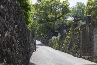 Dar taş patika uzun antik duvarlar arasında dönüyor.