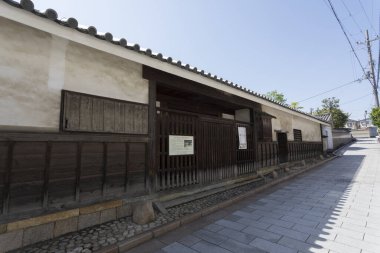 Geleneksel Japon ahşap binası berrak gökyüzünün altındaki sessiz taş sokak boyunca.