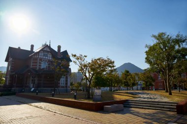 Ağaçlarla çevrili tarihi bina ve berrak mavi gökyüzü