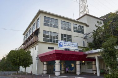 Geniş pencereleri ve giriş tepe örtüsü olan modern hastane binası.