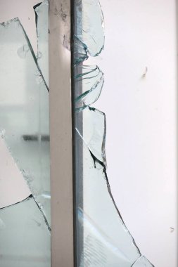 Metal çerçevenin yanında asılı kırık cam parçaları.