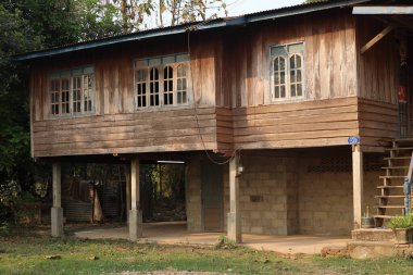 Gündüz vakti yeşil ağaçlarla çevrili ahşap ev.