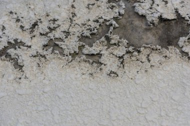 Beyaz boyanın duvardan sıyrıldığını gösteren desenli bir yüzey.