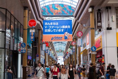 Şehirdeki hareketli alışveriş salonlarını keşfediyor.