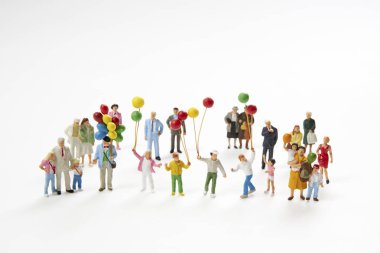 Beyaz tahta üzerinde balon tutan insanların minicik heykelcikleri.