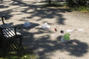 Boş park bankının yanındaki patika boyunca yayılmış çöp.