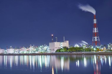 Aydınlatılmış fabrika Japonya 'nın alacakaranlık saatinde nehre yansıyor. Sanayi geçmişi  