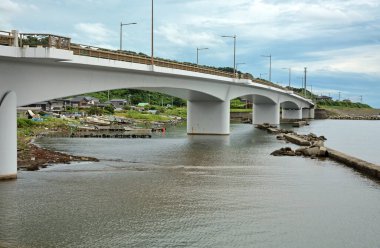 Sahil manzarası yakınlarındaki sakin su üzerinde uzanan köprü