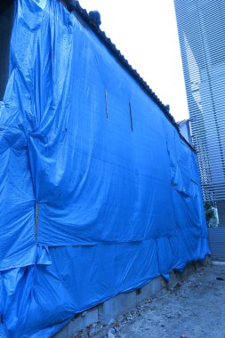 Şehirde inşaat halindeki mavi muşamba kaplı bina.