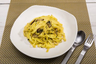 Mantarlı tagliatelle makarna ve beyaz tabakta ıspanak.