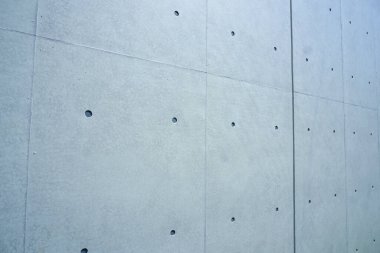Düz beton duvar, küçük yuvarlak delikler ve doku gösteriyor.