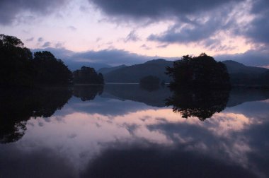 Arka planda birkaç ağaç ve dağ olan bir göl.